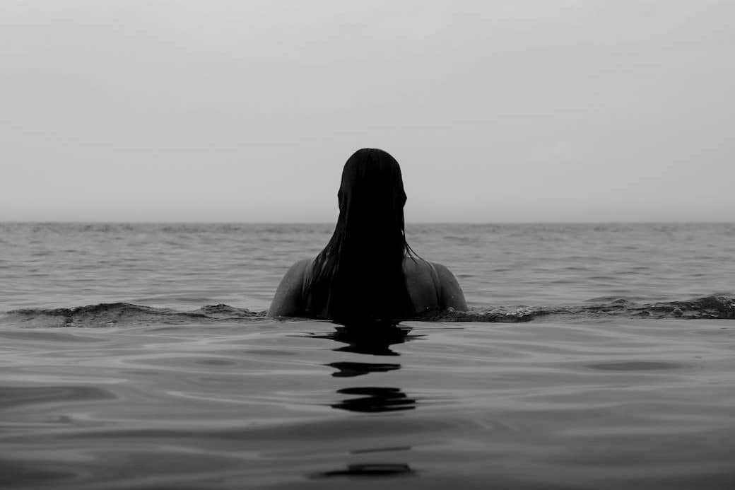 faceless woman in calm ocean water