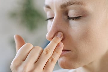 woman in black tank top touching her nose
