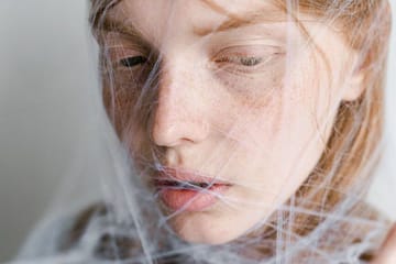 close up photo of a helpless woman trapped in a spider web