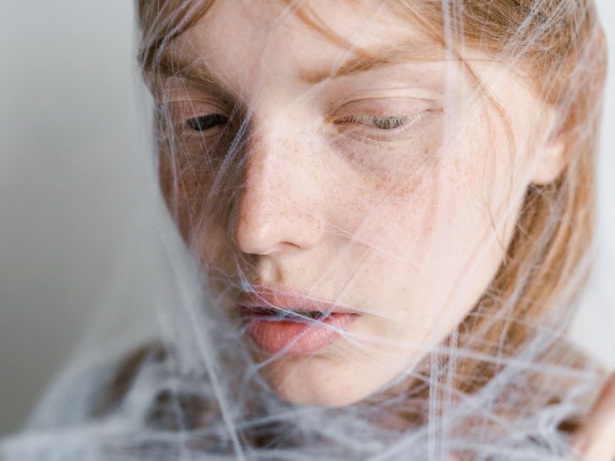 close up photo of a helpless woman trapped in a spider web
