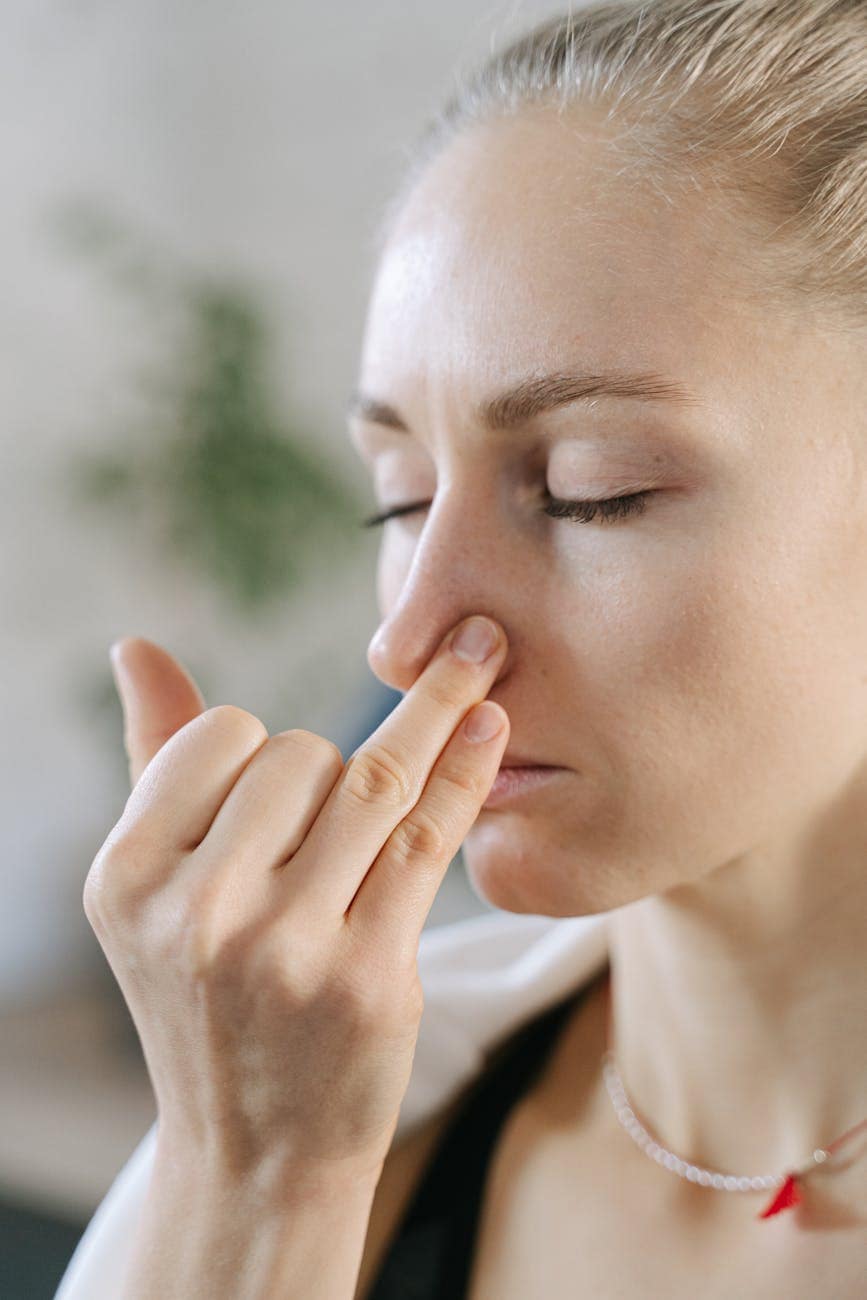 woman in black tank top touching her nose